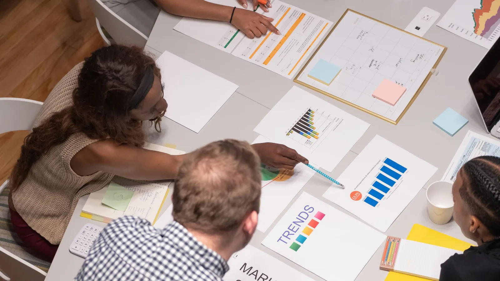 Team reviewing strategy, research and performance charts around a table