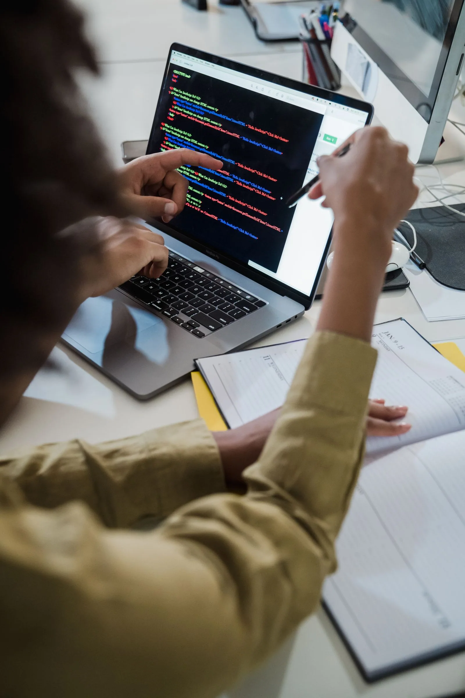 Web designers and developers reviewing website code together on a laptop